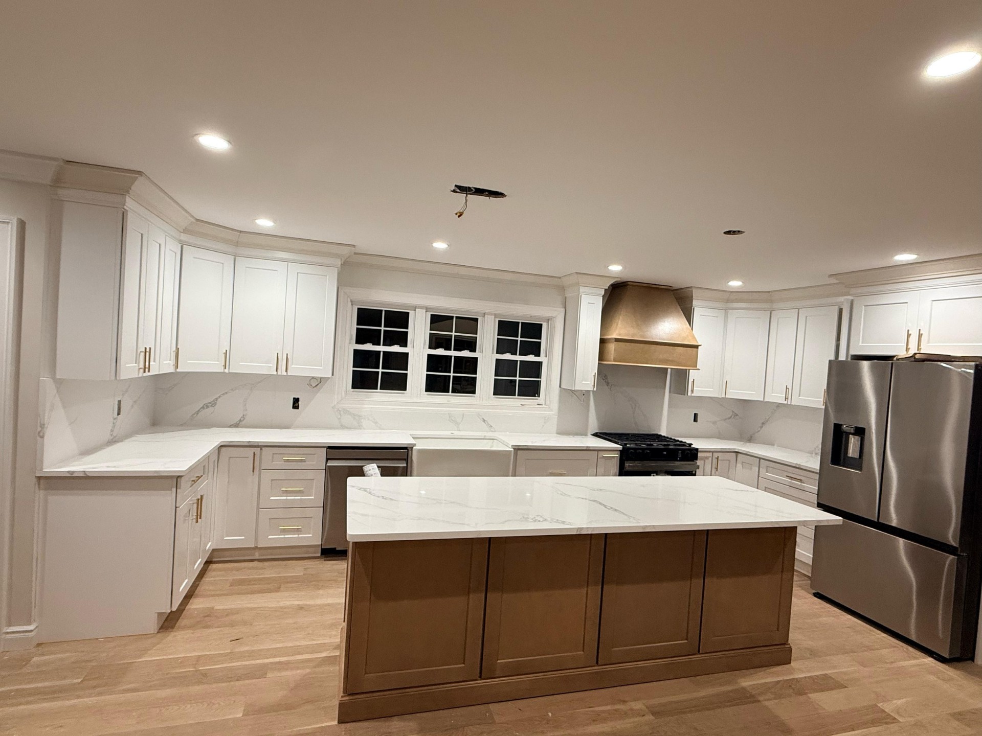 Bright white kitchen with warm walnut island and marble countertops installed by ABT Kitchen Cabinets