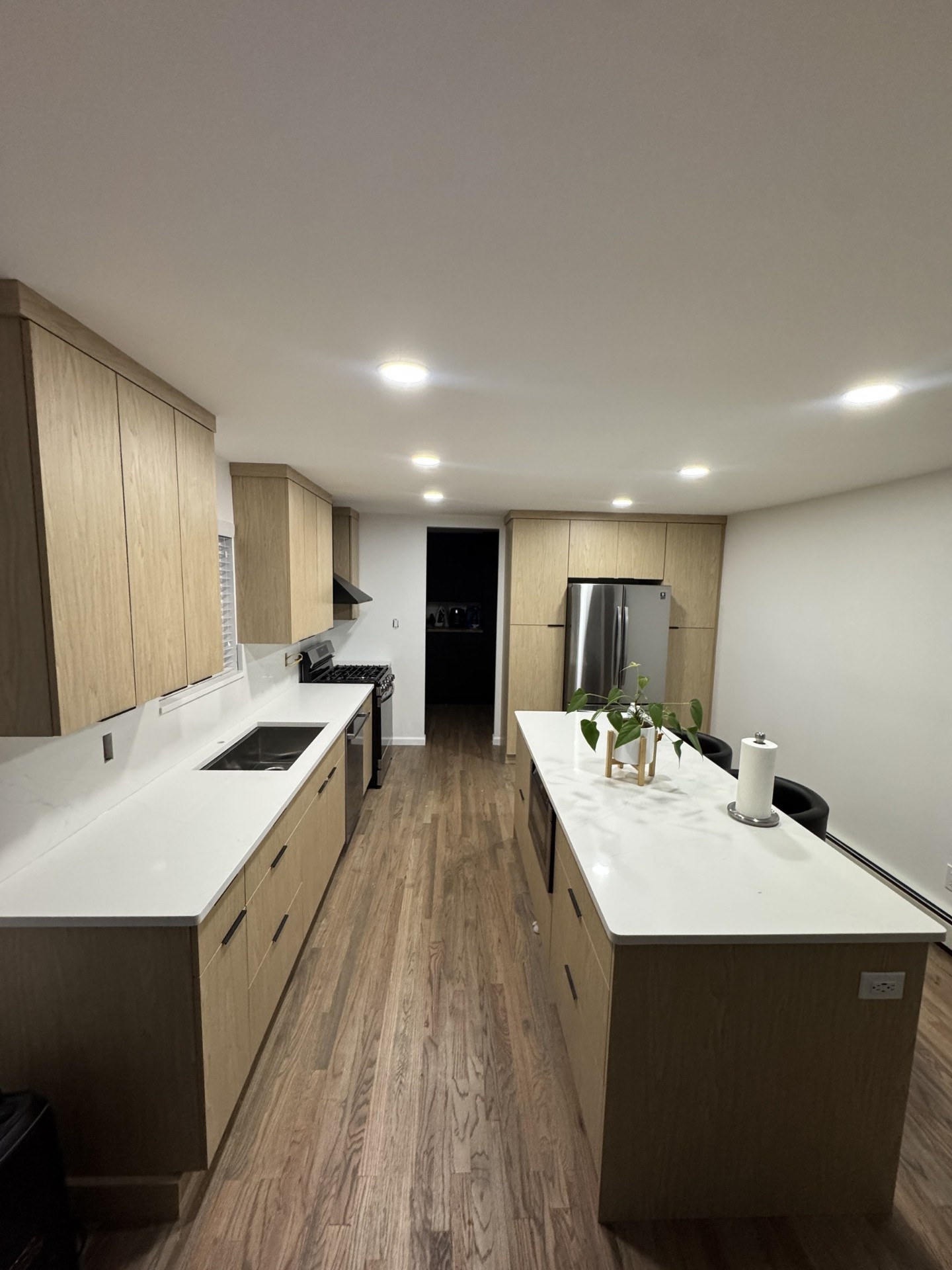 Modern natural oak galley kitchen with white quartz countertops and wood floors
